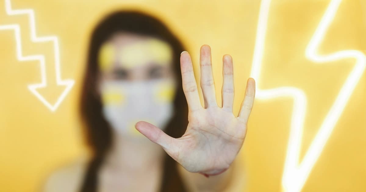 Person with mask, electricity symbol and sinking chart in the background